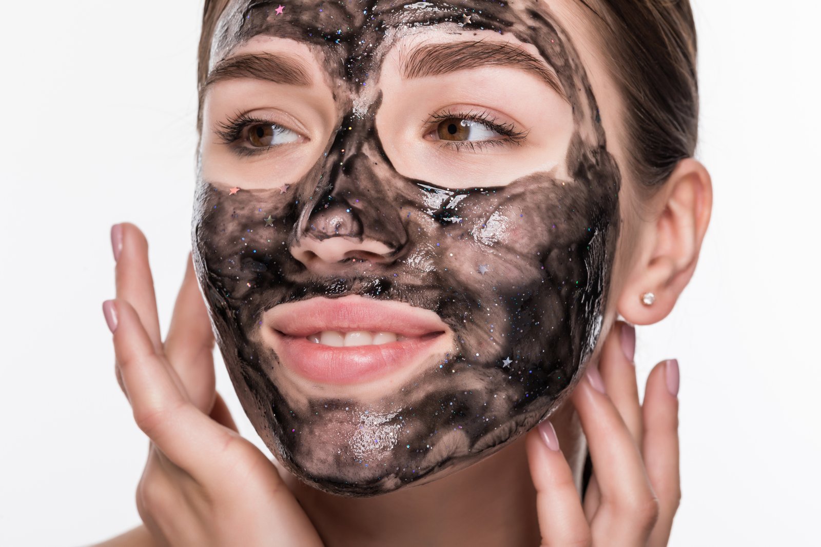 Smiling young woman with a carbon peel mask applied, showcasing clear and rejuvenated skin after a professional treatment.