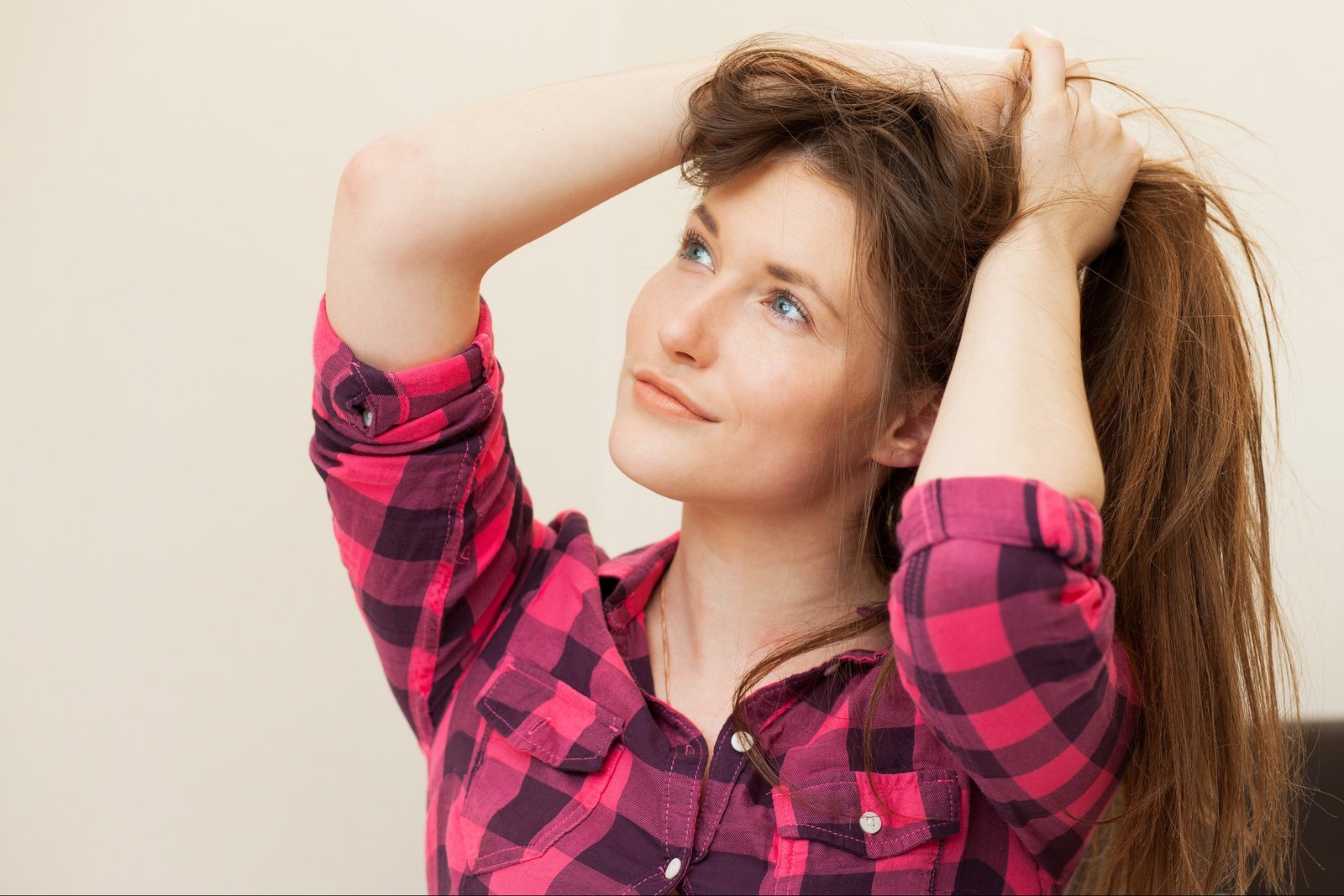 Smiling young woman running her fingers through her healthy, dandruff-free hair, enjoying the results of effective solutions to rid of dandruff permanently.