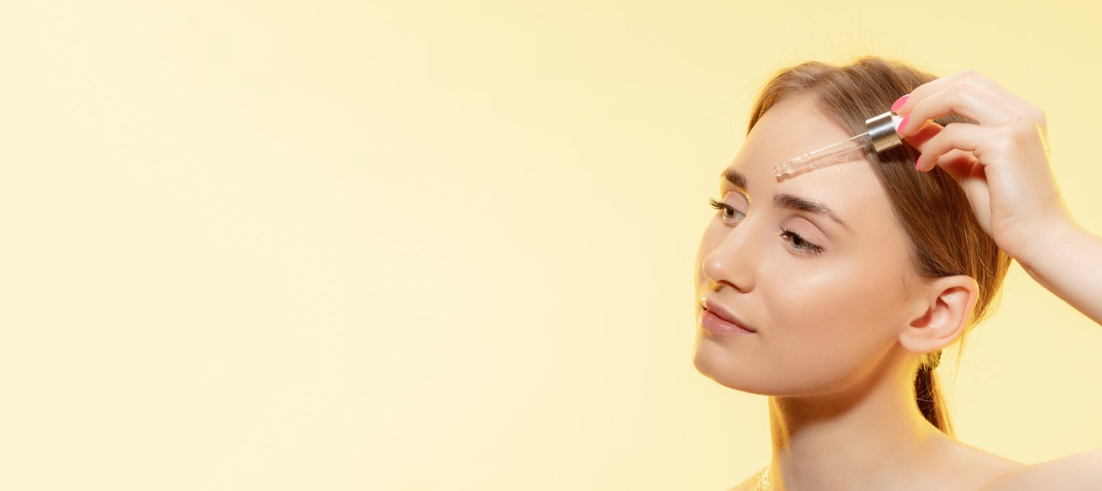 Young woman applying Glutathione serum for radiant and glowing skin on a yellow background.